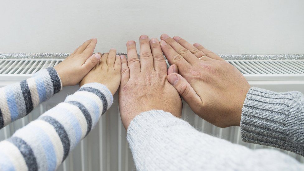 Father and son warming their hands over a radiator