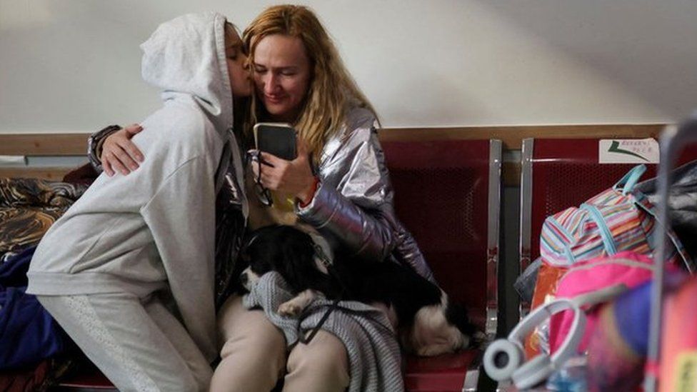 Ukrainian refugee Olena Kalynovska looks at an image of her husband after disembarking a train in Bucharest