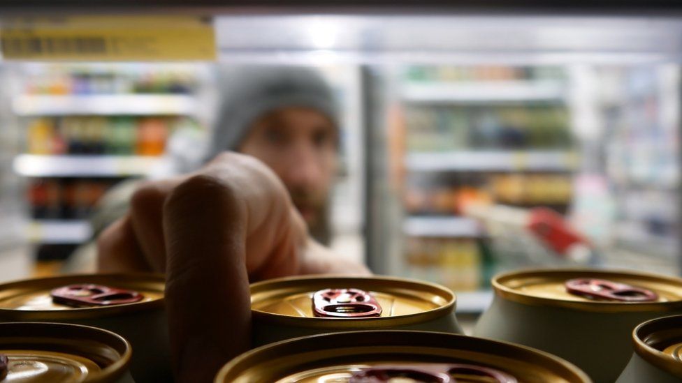 Close-up of a man taking a beer from a supermarket fridge