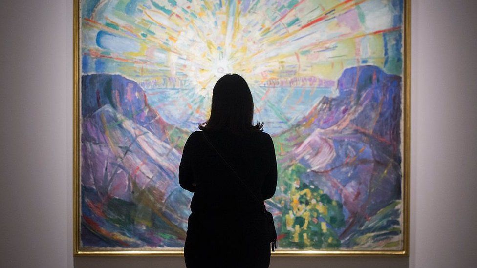 A woman looking at a large painting in an art gallery