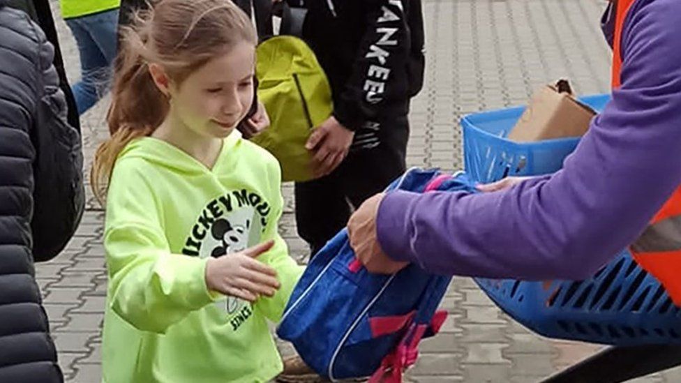 Child being handed a backpack in Poland