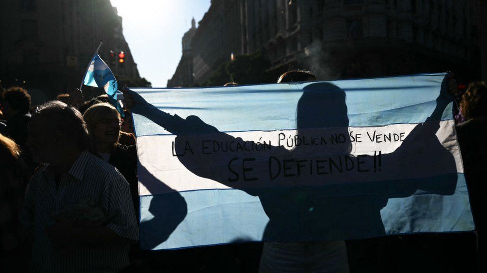 A woman's silhouette is seen on an Argentinian flag during protests in Buenos Aires against university cuts.