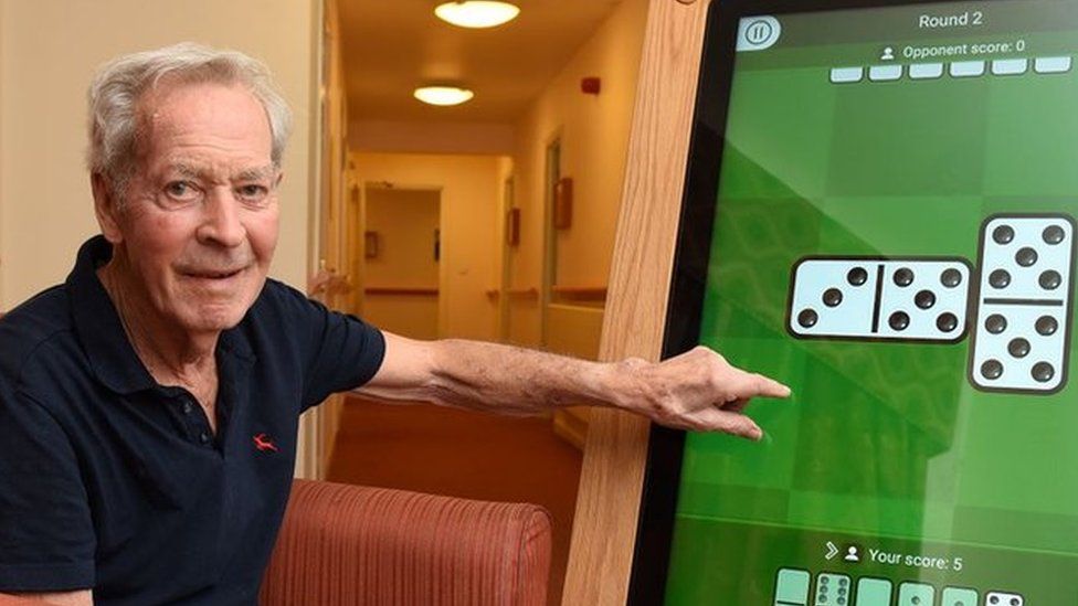 Down Hall resident Stanley playing dominoes on a giant tablet.