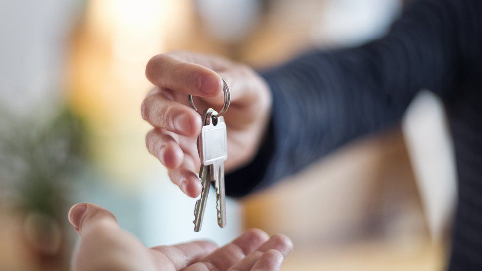 Person handing over house keys (stock photo)