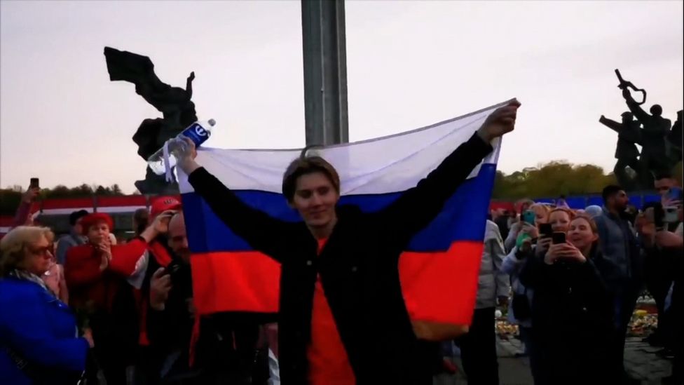 Alexander Dubyako waves a Russian flag for the crowd assembled in front of Riga’s war memorial on 10 May 2022