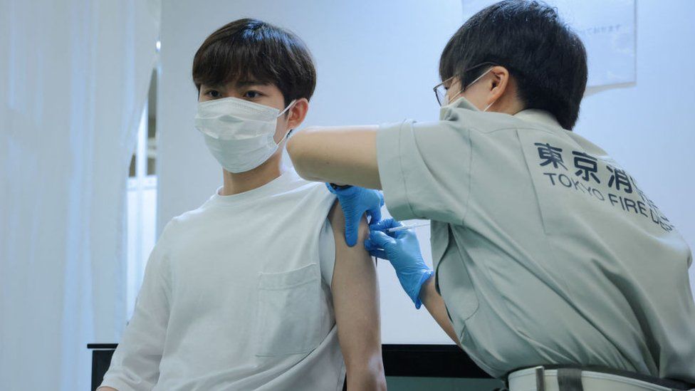 A Tokyo fire brigade staff member (right) administers a dose of the Covid-19 coronavirus vaccine at Aoyama University in Tokyo on August 2, 2021
