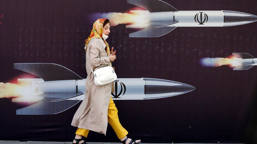 An Iranian woman walks past a huge anti-Israeli banner carrying pictures of missiles, in Tehran, Iran, 19 April 2024.