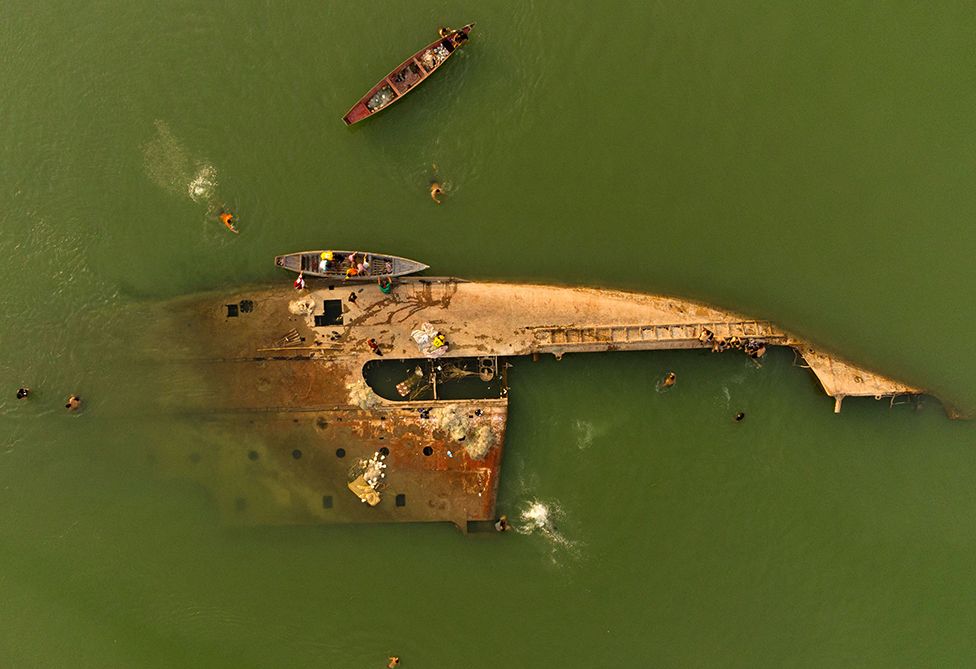 An aerial picture taken by drone shows young Iraqis swimming in the Shatt al-Arab waterway near a shipwreck in the southern city of Basra on 6 June 2022