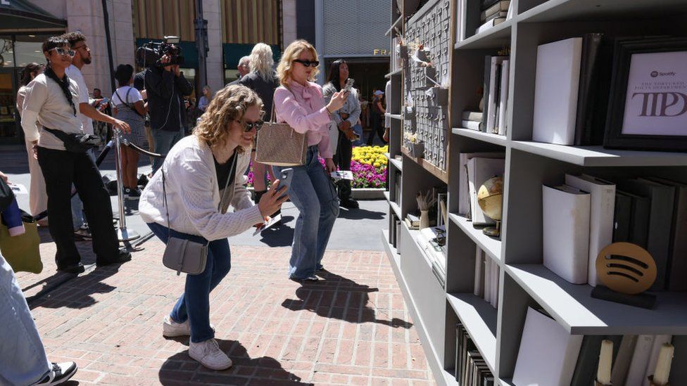 Women taking photographs of a Taylor Swift pop-up store