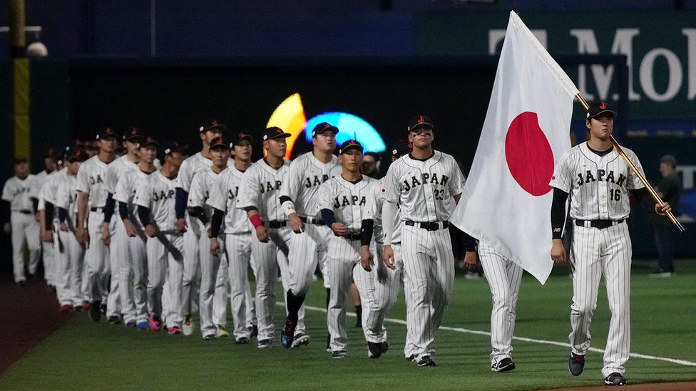 Shohei Ohtani leads his teammates onto the field while carrying the Japanese flag prior to the game against the United States.