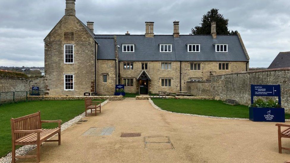 Chester House - a three-storey Northamptonshire stone manor house with gravel path and benches in front