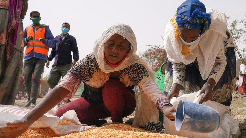 Woman scooping up lentils during an aid operation in Mekelle