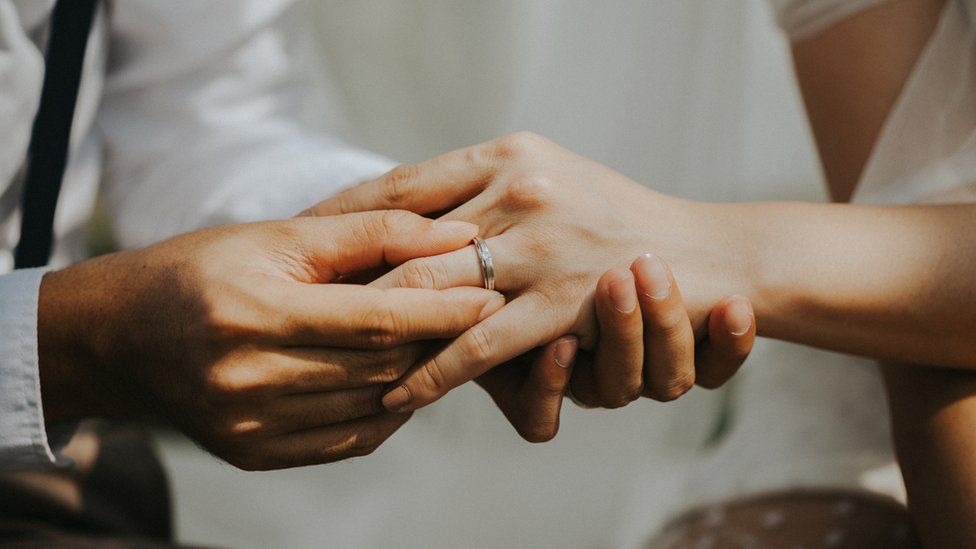 Couple's hands exchanging ring