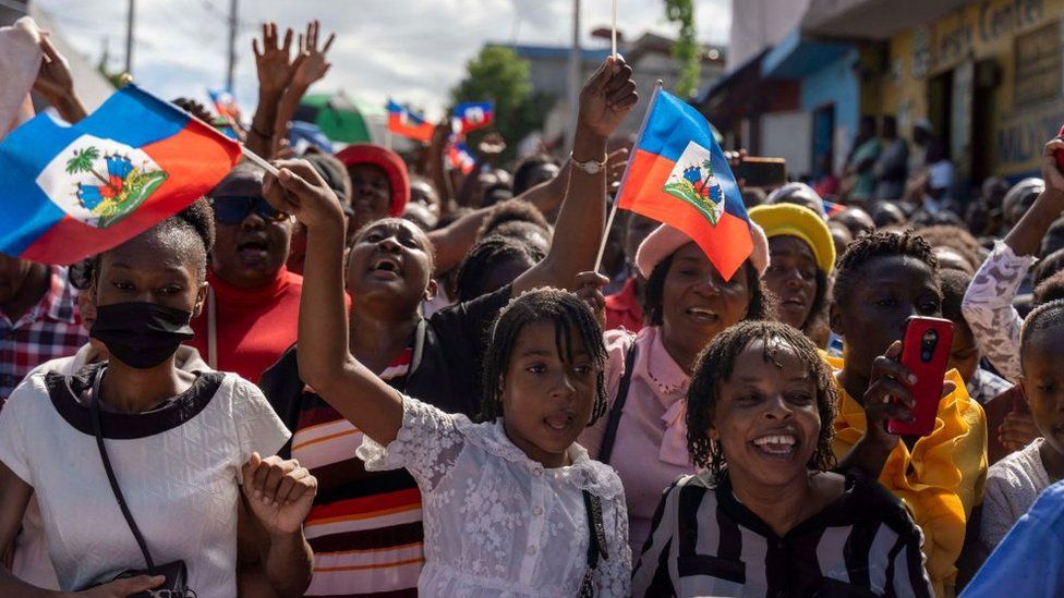 People wave flags and march during a rally to denounce the high levels of crime in Port-au-Prince, Haiti, October 30, 2022