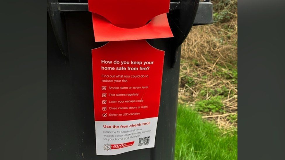 Image of a bin hanger. It is red and lists ways in which residents can reduce the risk of home fires. The Avon Fire and Rescue logo is printed across the bottom of the hanger.