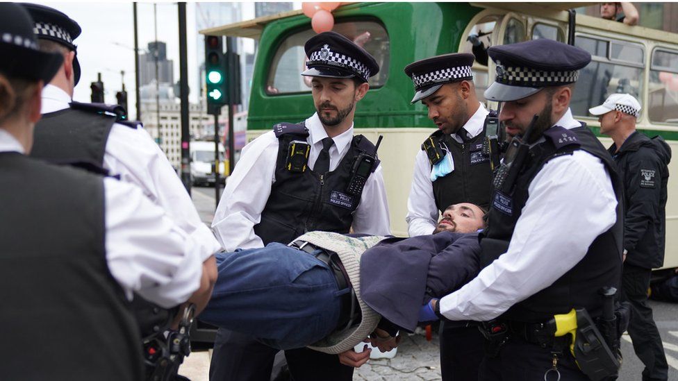 Police remove a demonstrator from a bus parked on London Bridge