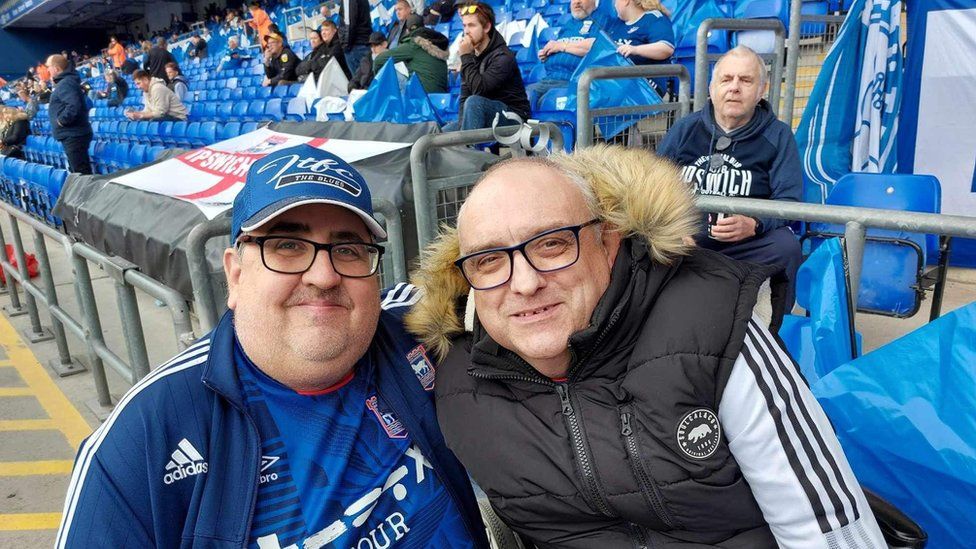 Steve Kirby and Gary Battle standing in the Sir Bobby Robson stand ahead of an Ipswich Town game. Both wearing Ipswich Town clothing