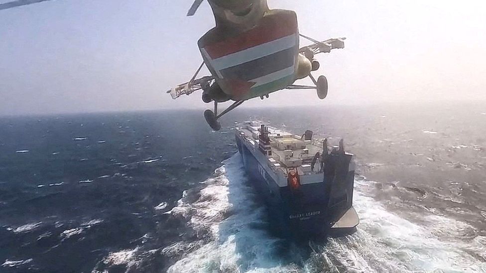 A Houthi military helicopter flies over a cargo ship in the Red Sea