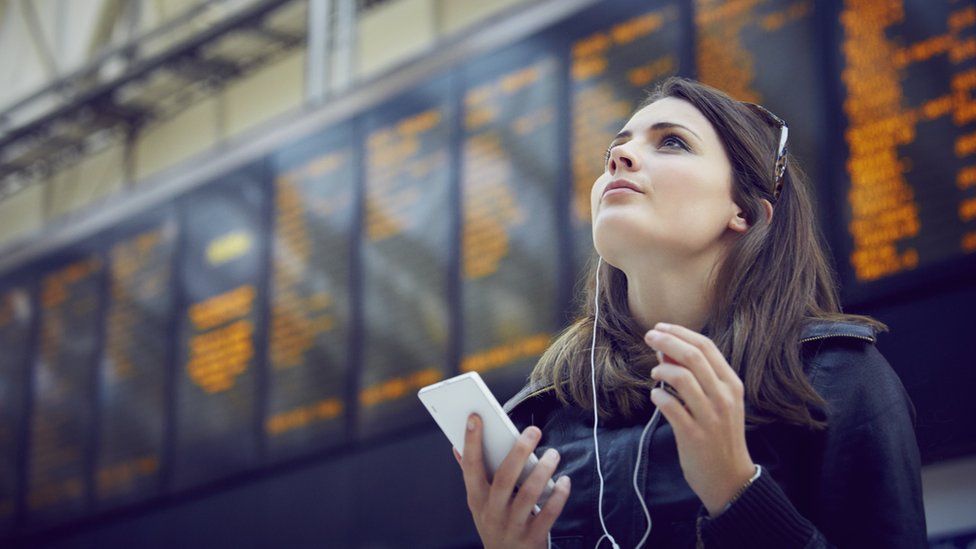 Woman looks at train departures board