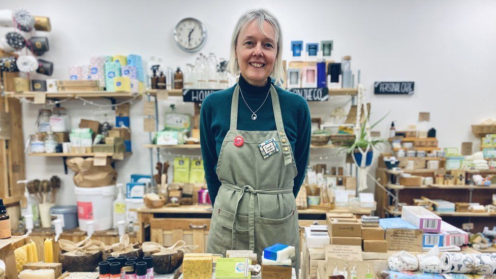 Owner of the shop standing behind a table filled with eco-friendly products
