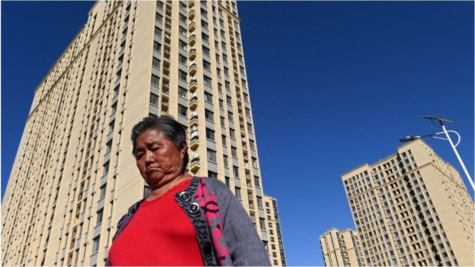 A woman walks in front of a housing complex by Chinese property developer Evergrande in Beijing
