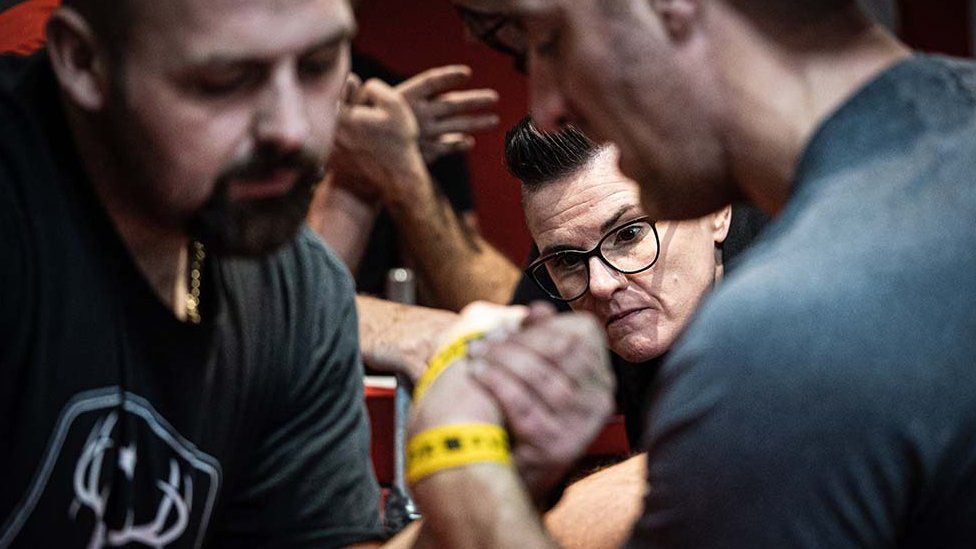 Arm wrestlers competing whilst referee watches