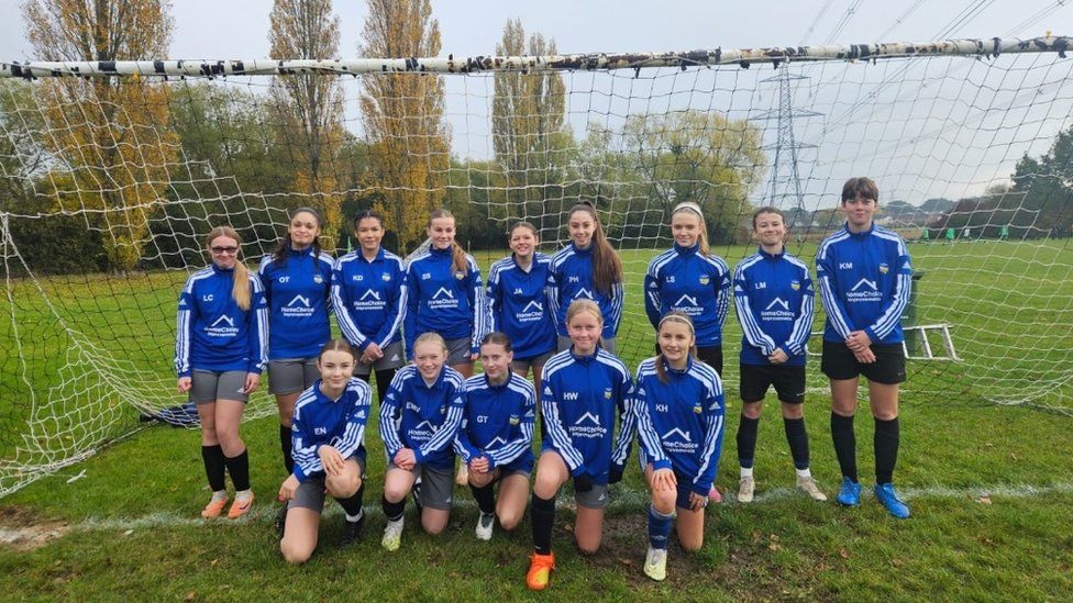 Concord Rangers U14 girls' team. They are wearing a blue football kit and standing by a goal post in a field