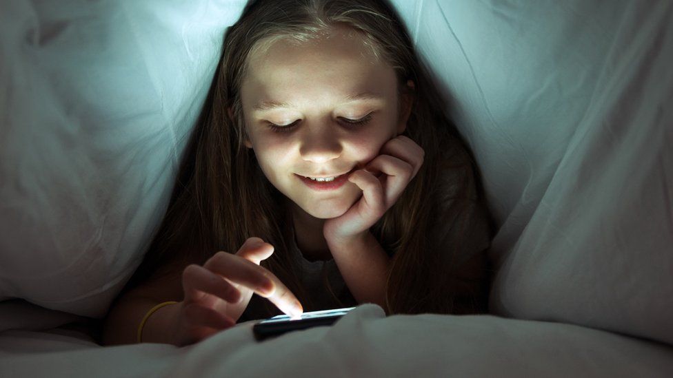 Girl looking at phone in bed.