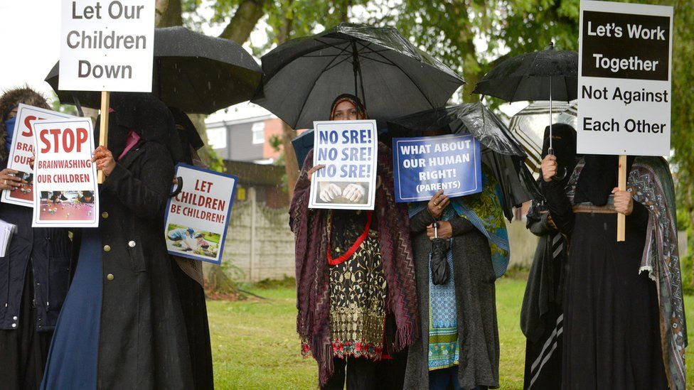 Protesters hold signs and placards during their first demonstration after an injunction barred action immediately outside Anderton Park Primary School