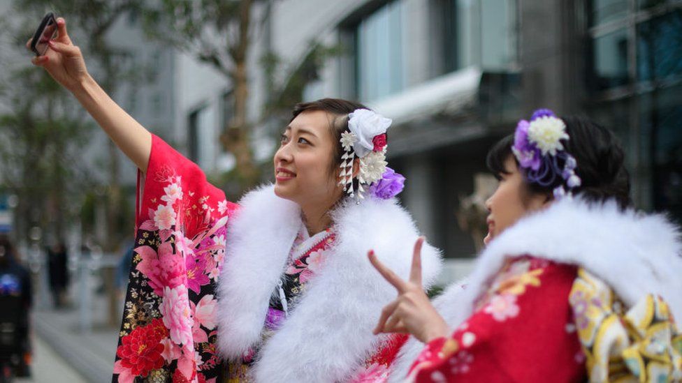 Women wearing kimonos take a selfie attending a Coming of Age ceremony on January 8, 2018 in Yokohama, Japan.