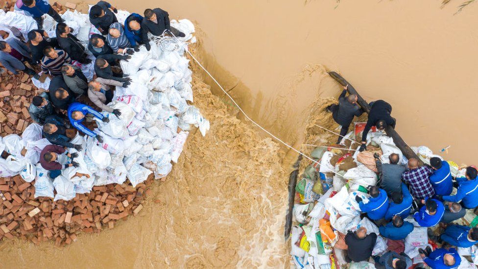 Aerial view of people working to block a dyke breach at a section of Fenhe River in Jishan County.