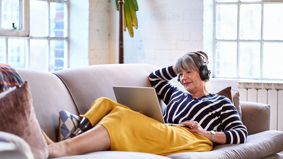 woman wearing headphones watching movie on laptop