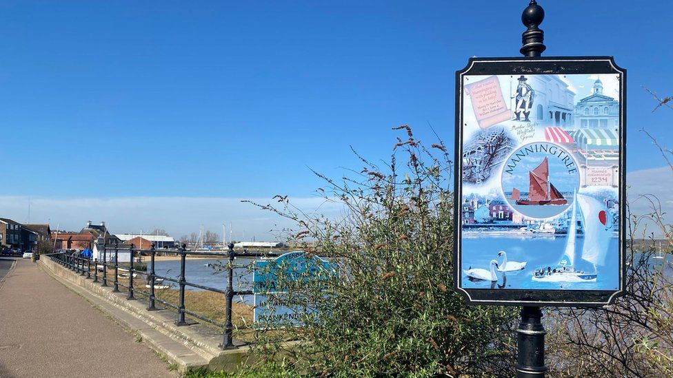 Manningtree sign with beach in the background