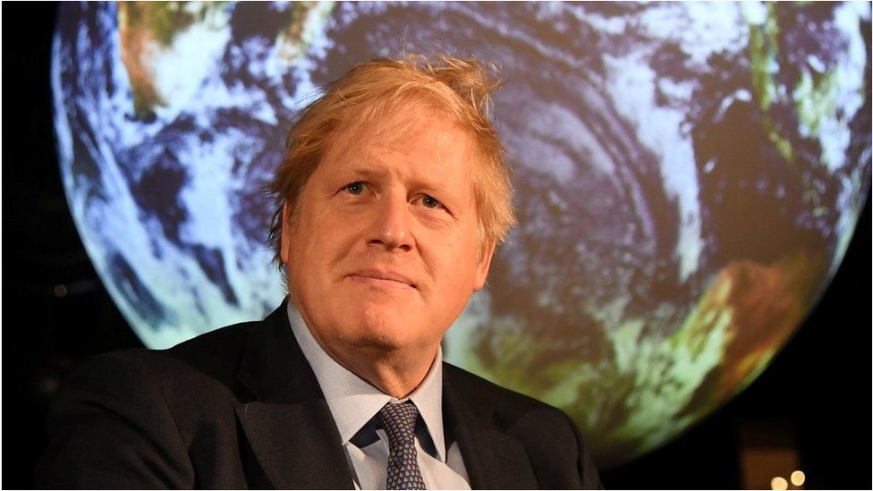 Boris Johnson in front of a globe at a meeting ahead of COP26