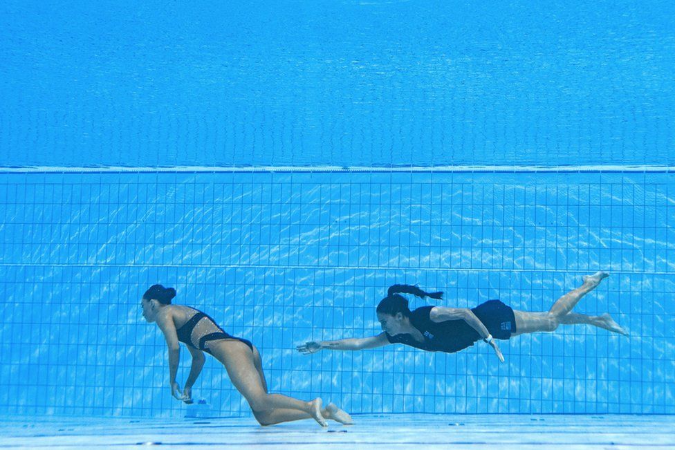 SA's coach Andrea Fuentes (R) swims to recover USA's Anita Alvarez (L), from the bottom of the pool during an incident in the women's solo free artistic swimming finals, during the Budapest.