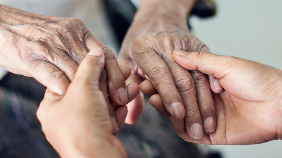 Carer holding elderly person's hands