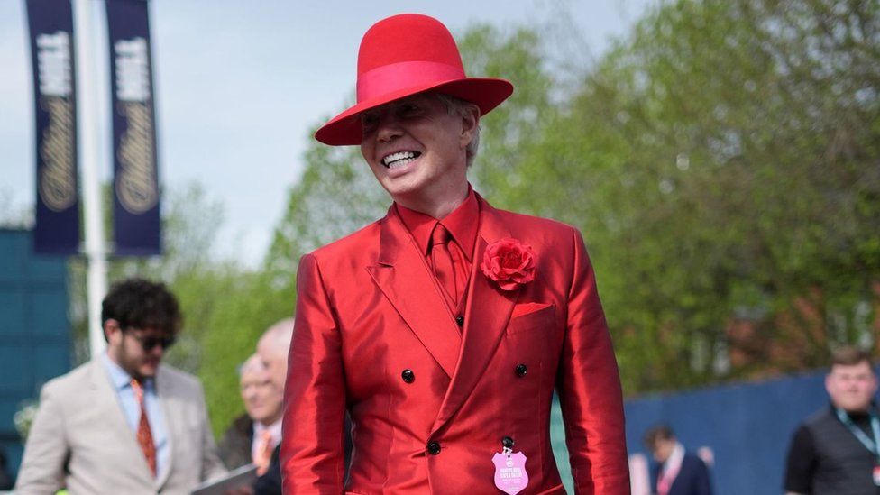 Racegoer dressed in red suit and matching hat at Aintree Ladies Day 2024