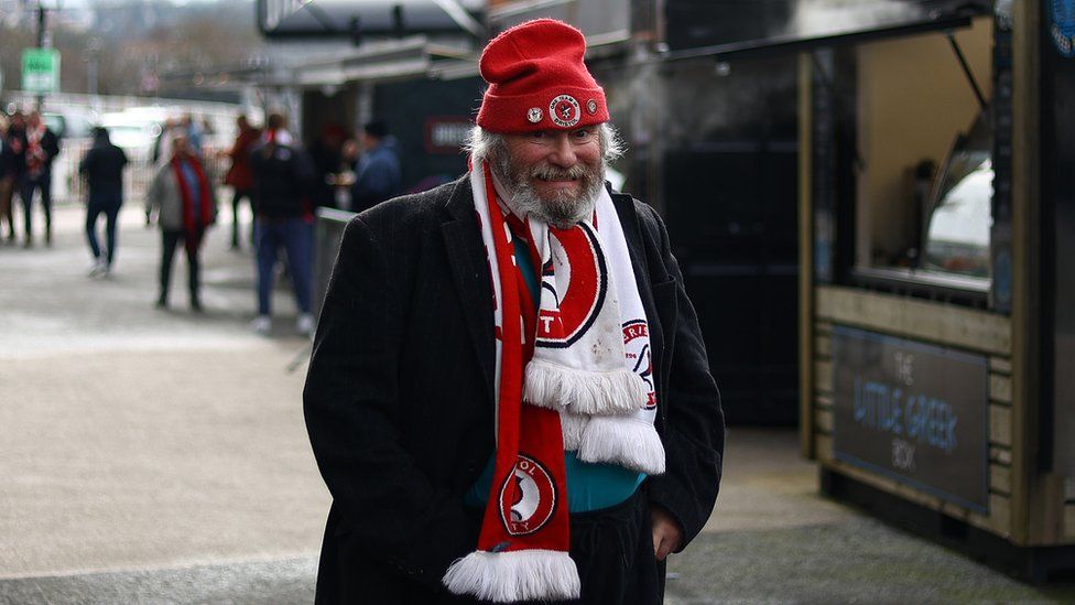 A Bristol City fan with a white beard wearing red and white scarf and hat at Ashton Gate