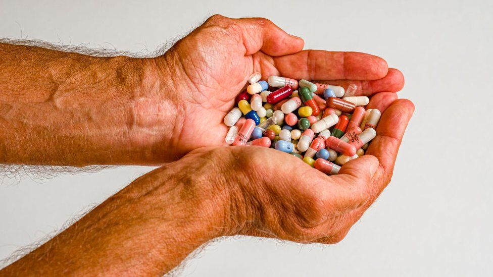 A man holding two handfuls of pills