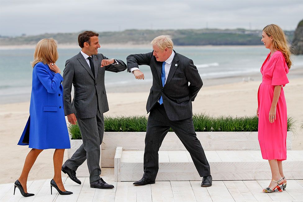 Prime Minister Boris Johnson greet France's President Emmanuel Macron with an elbow bump as their spouses look on in Cornwall, during the G7 summit