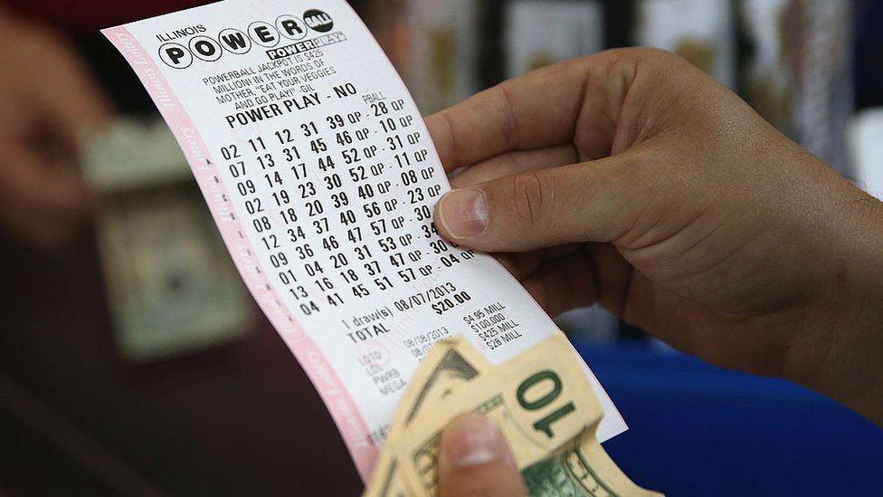 Image shows a woman holding her Powerball ticket