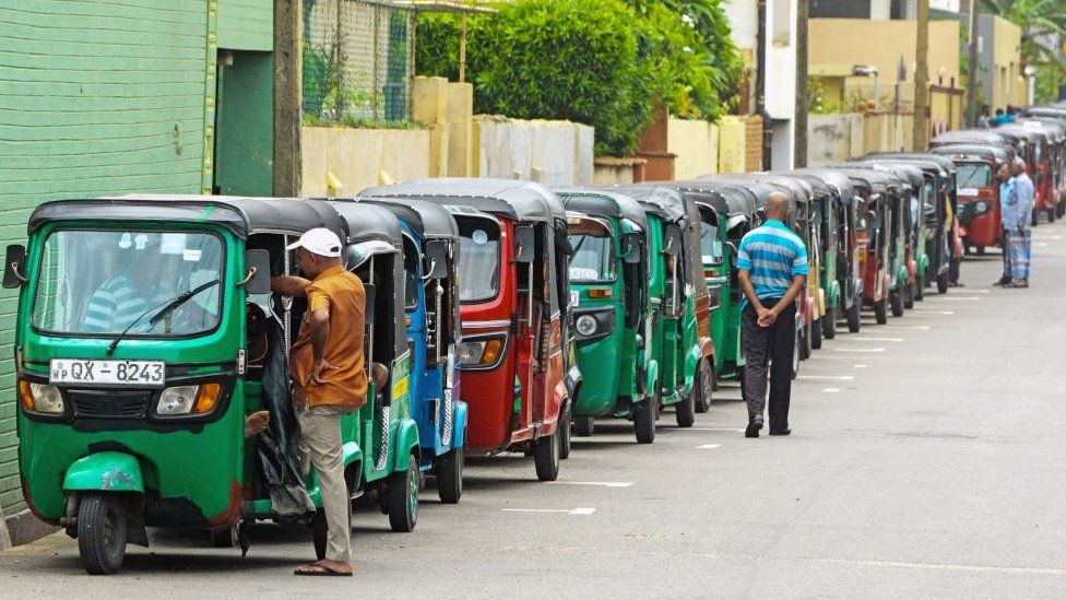 Auto rickshaw drivers queue along a street to buy fuel at a fuel station in Colombo.