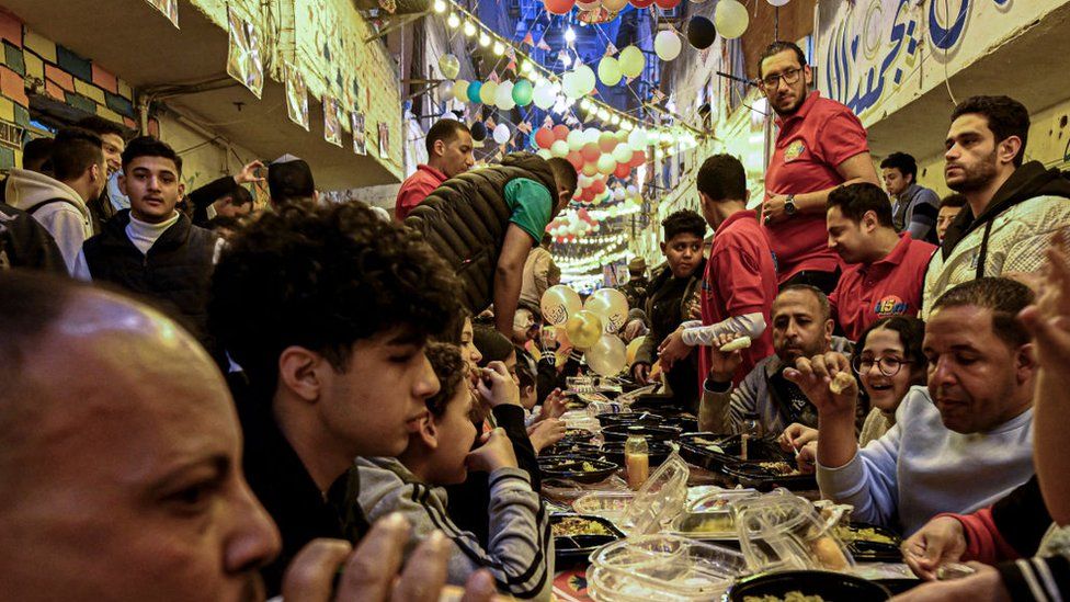 Egyptian Muslims gather in streets lined with long tables to break their fast together in a mass "iftar" meal in Ezbet Hamada in Cairo's Matariya suburb on March 25, 2024