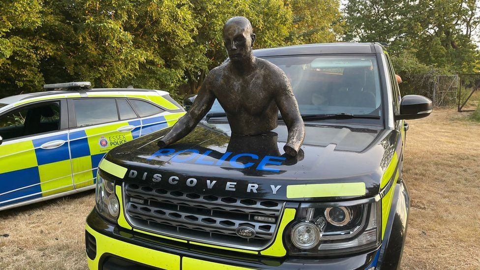Top half of mannequin on top of police land rover bonnet