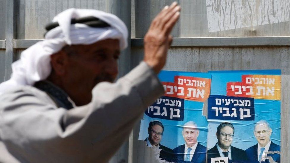 Palestinian gestures next to Israeli election posters in Hebron (07/09/19)