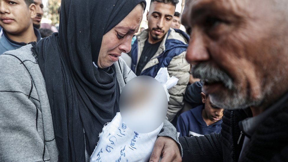 The mother and grandfather of Muhammad Hani al-Zahar, holding his swaddled body and grieving after his death