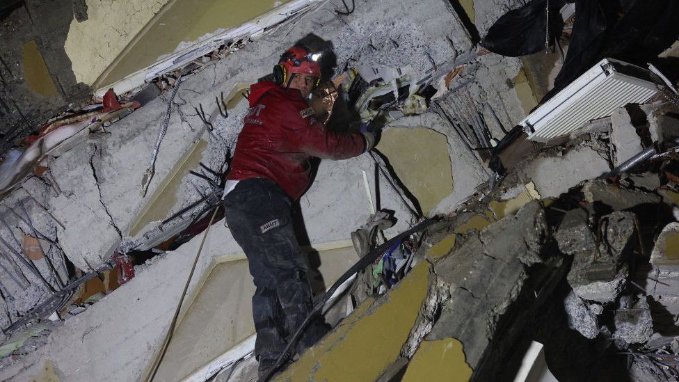 A rescuer searches for victims and survivors amidst the rubble of collapsed buildings in Kahramanmaras, Turkey