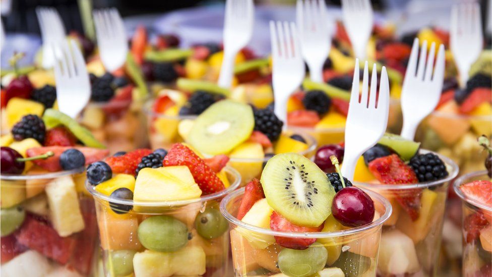 Fruit salad served in plastic cups with plastic forks