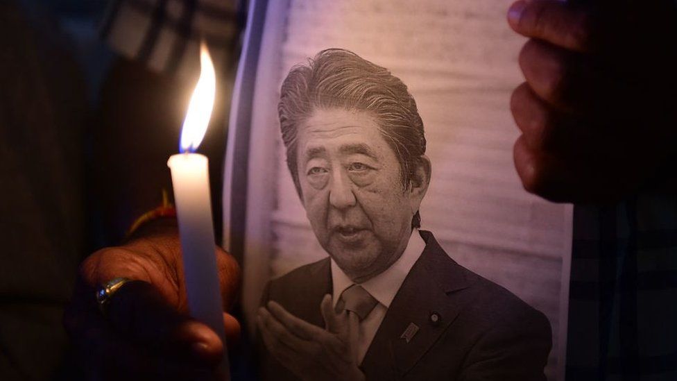 Members of the Japan information and study centre hold a candlelight vigil to pay tribute to the late former prime minister of Japan Shinzo Abe, at Ahmedabad Management Association in Ahmedabad on July 9, 2022, after Abe was shot dead during a campaign speech on July 8 in Nara.