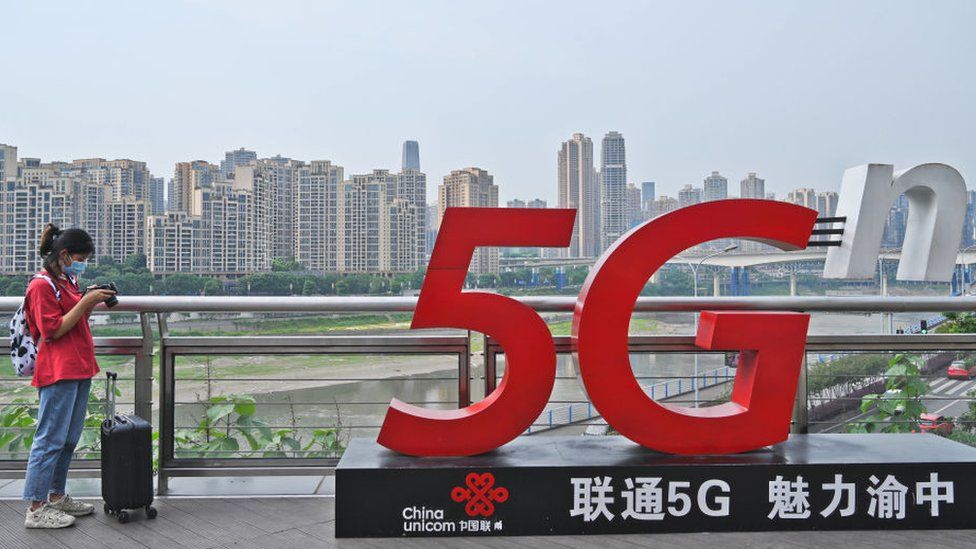 A woman stands beside a China Unicom 5G sign in Chongqing, China.